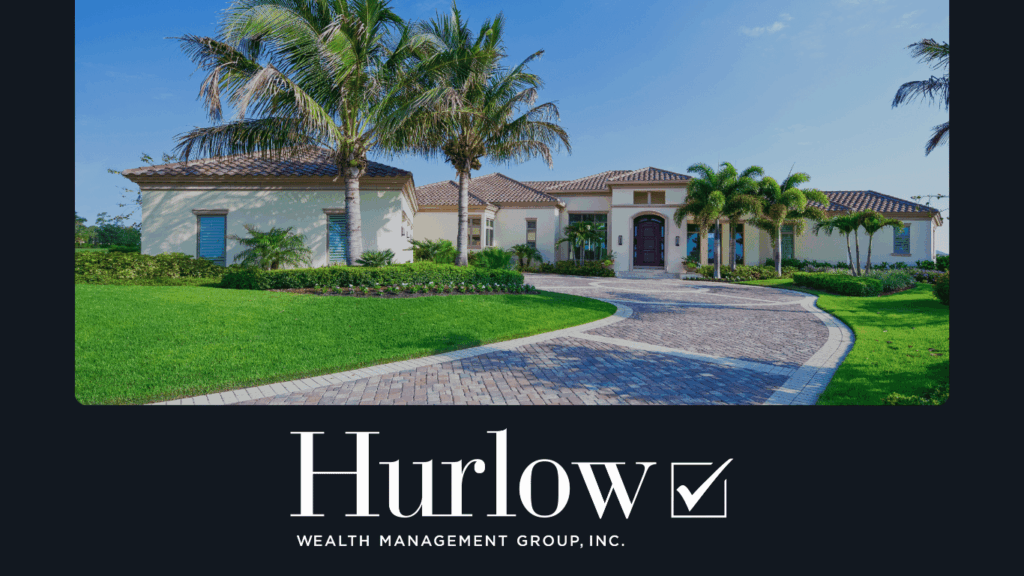 A driveway leading to a large house surrounding by palm trees